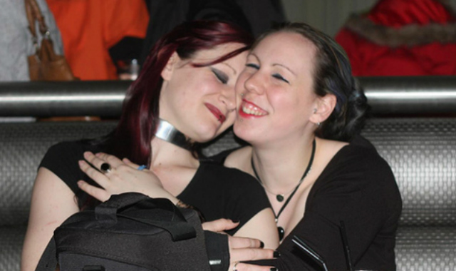 Two women sitting in a booth, smiling with each other