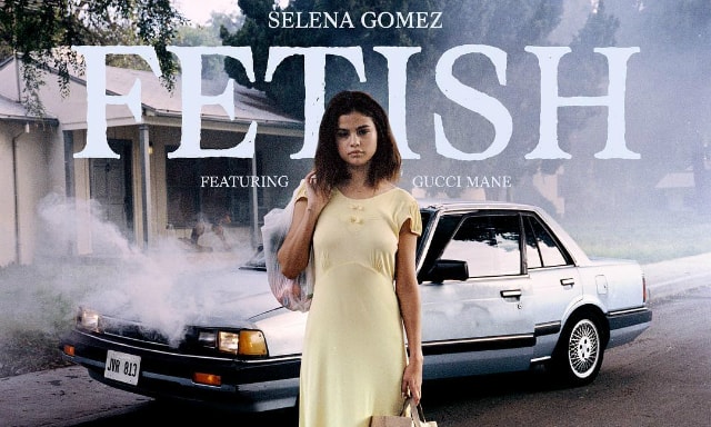 Selena Gomez standing in front of a smoking car carrying shopping bags