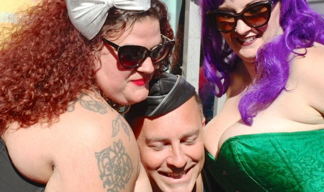 Image of a man squeezed between two women's breasts