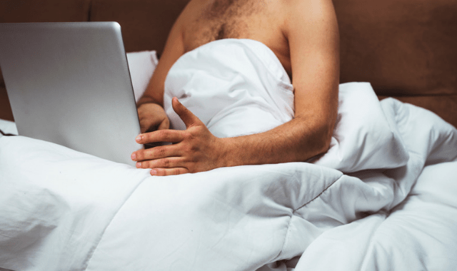 Man with a femdom fantasy in bed with laptop