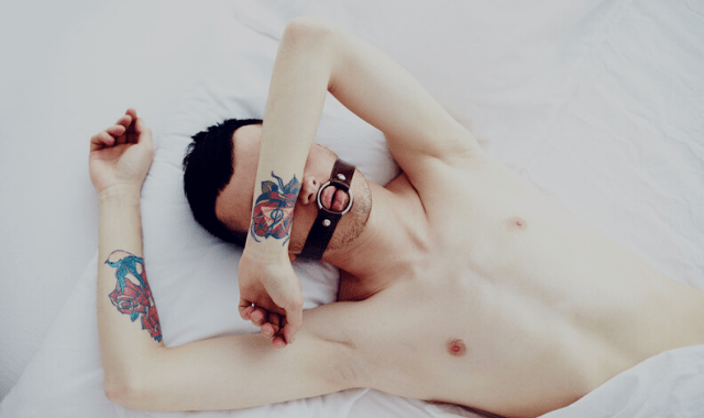 Male sub gagged on a bed